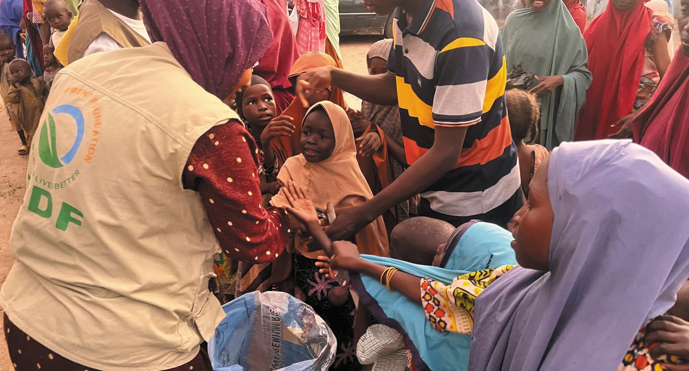 ZAIDF team members in ZDF vests assist families gathered at a distribution point