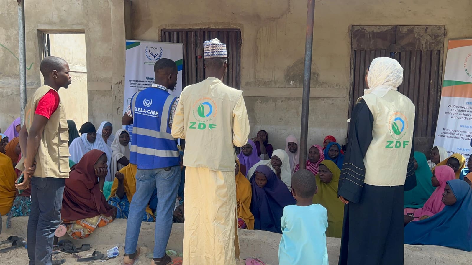 ZAIDF field team members in ZDF vests meet with girls and women seated outdoors in Abuja