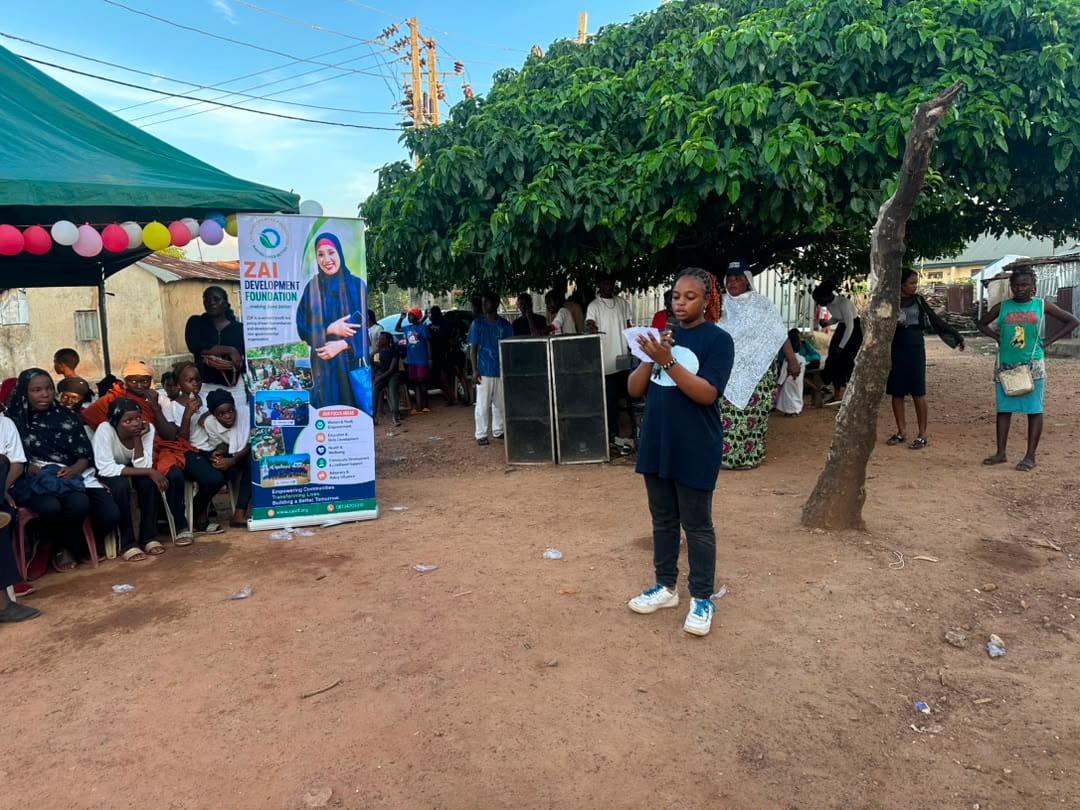 A facilitator presents in the shade of a tree beside the green canopies